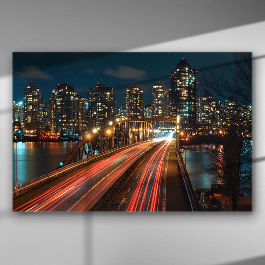 Cityscape at night with a bridge and light trails from cars
