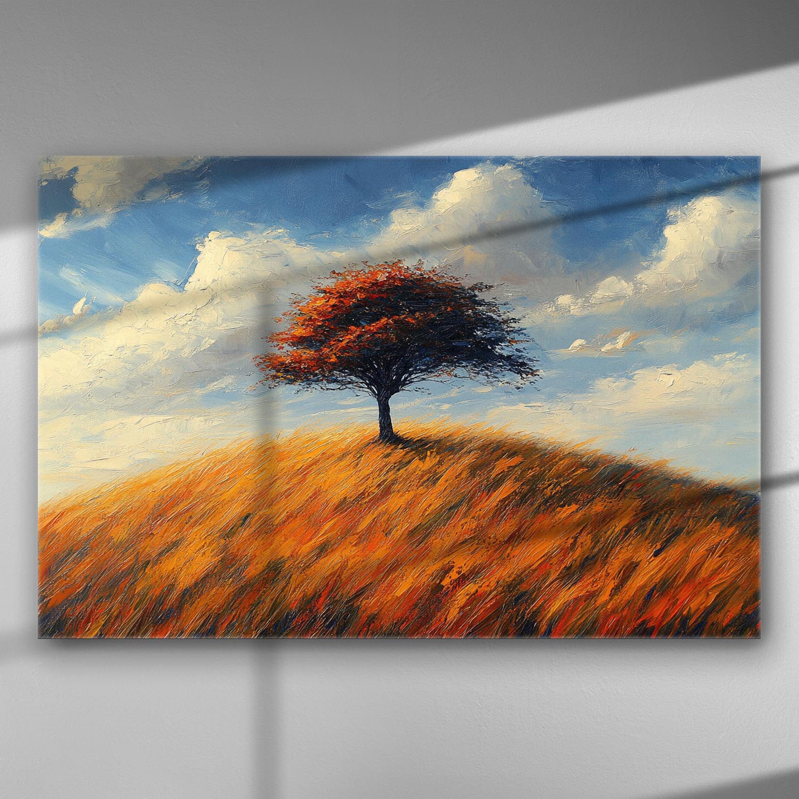 A lone tree on a hill with vibrant orange foliage against a blue sky.