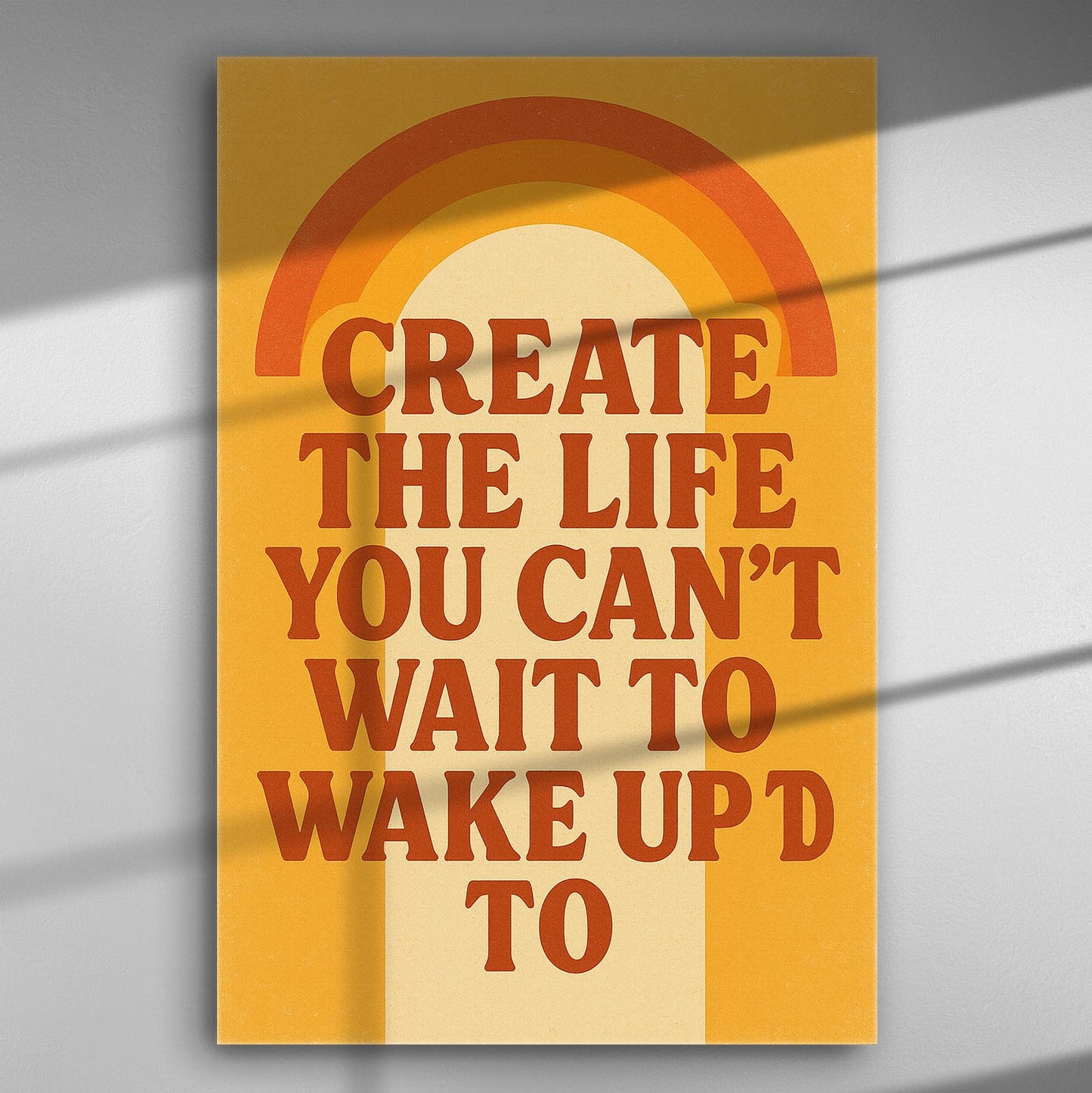 Motivational wall art with the phrase 'Create the life you can't wait to wake up to' in warm sunset colors.