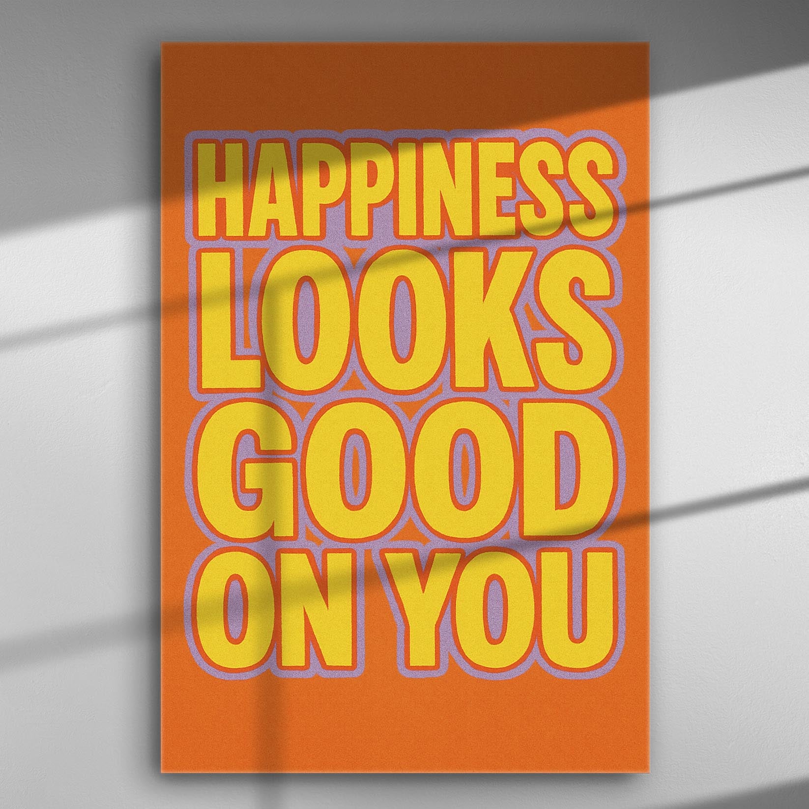 Canvas print with the text 'Happiness looks good on you' in bold yellow letters on an orange background.