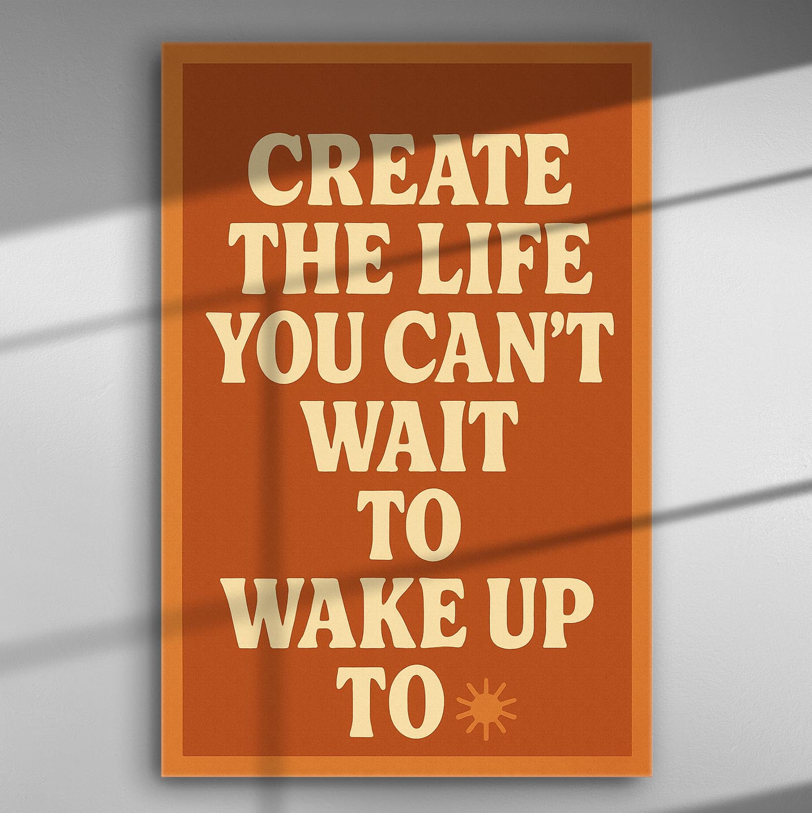 Canvas print with motivational quote 'Create the life you can't wait to wake up to' on an orange background.