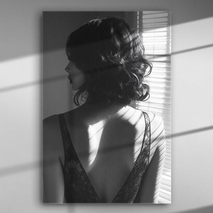 Black and white silhouette of a woman with light from blinds highlighting her back.