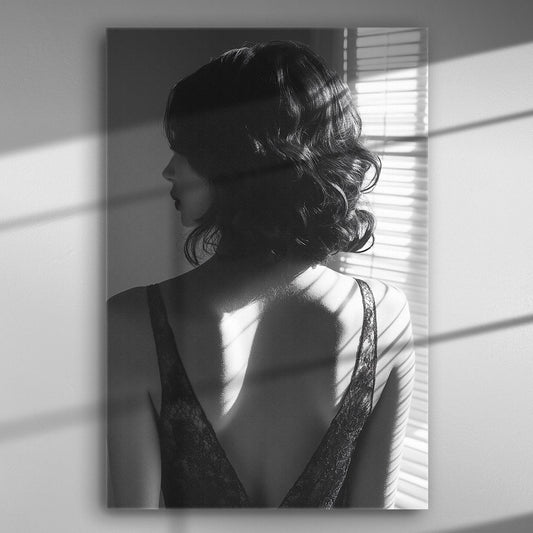 Black and white silhouette of a woman with light from blinds highlighting her back.
