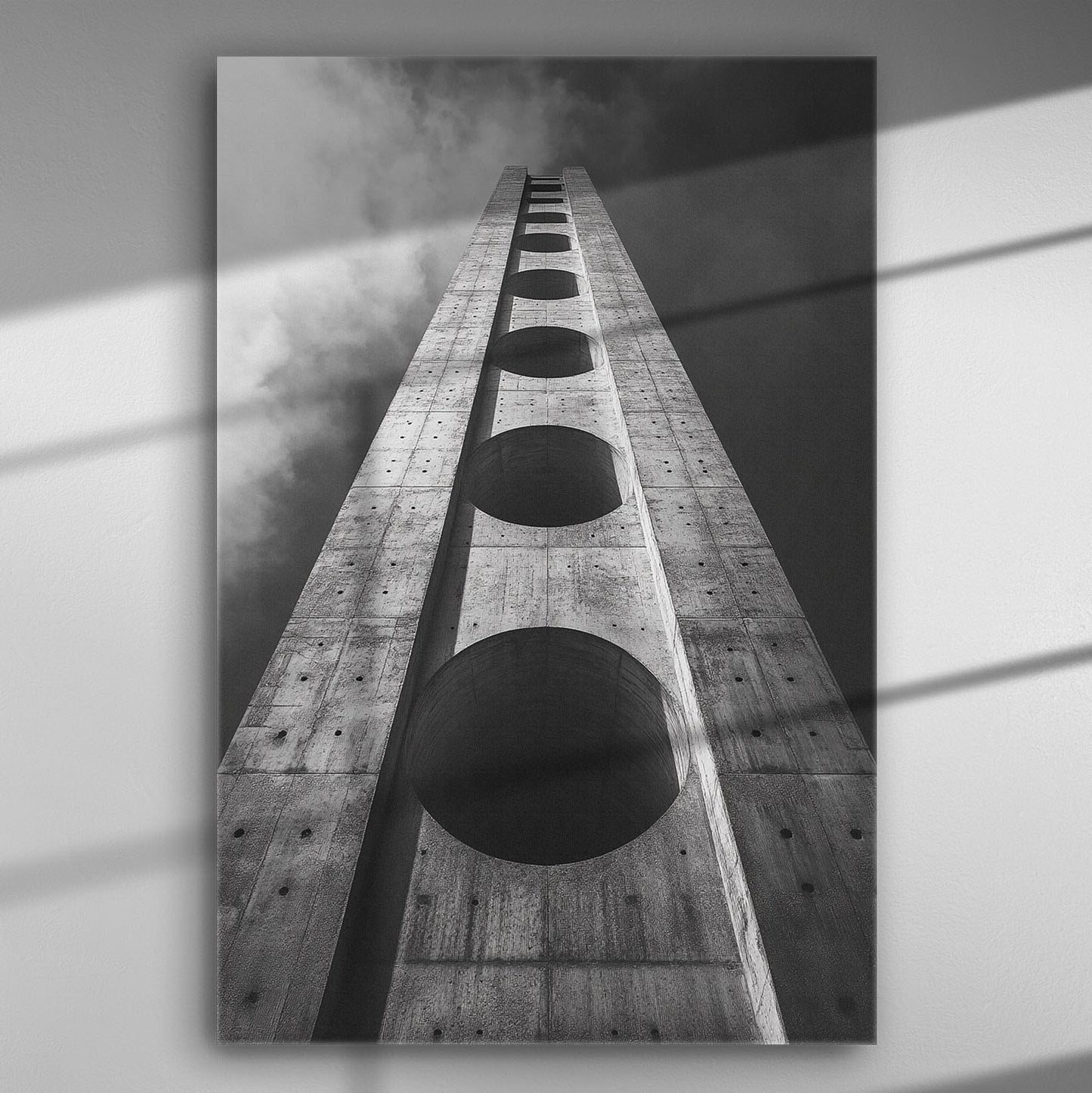 Black and white perspective photo of a skyscraper with geometric shapes looking upwards.