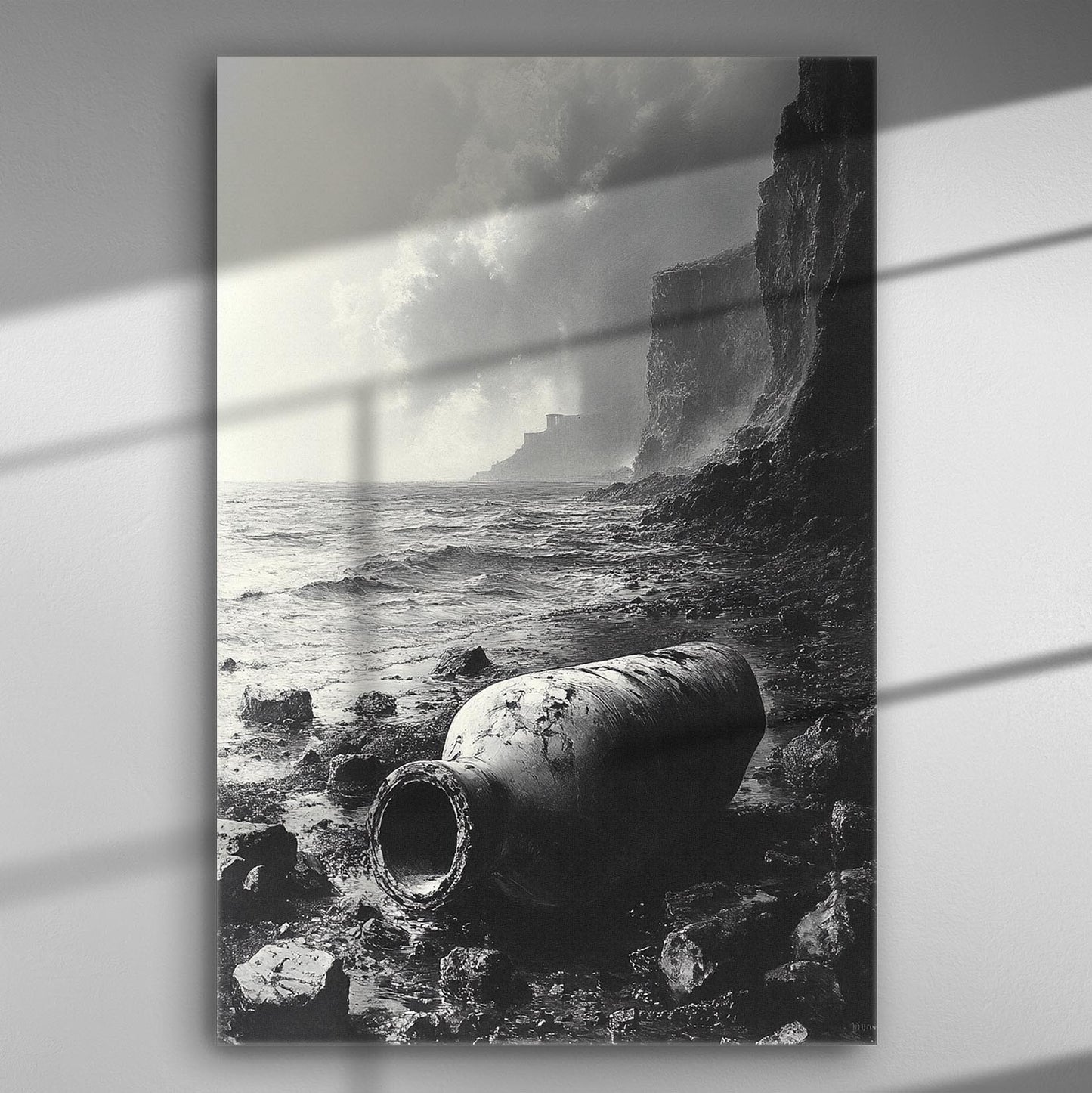 Black and white coastal scene with large amphora on rocky beach against dramatic sky.