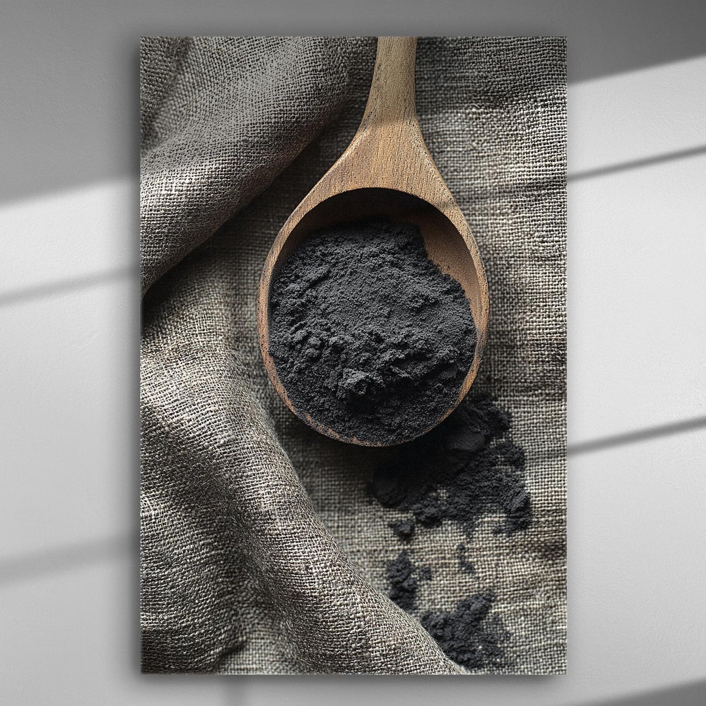 Wooden spoon with black powder on fabric surface, emphasizing natural textures.