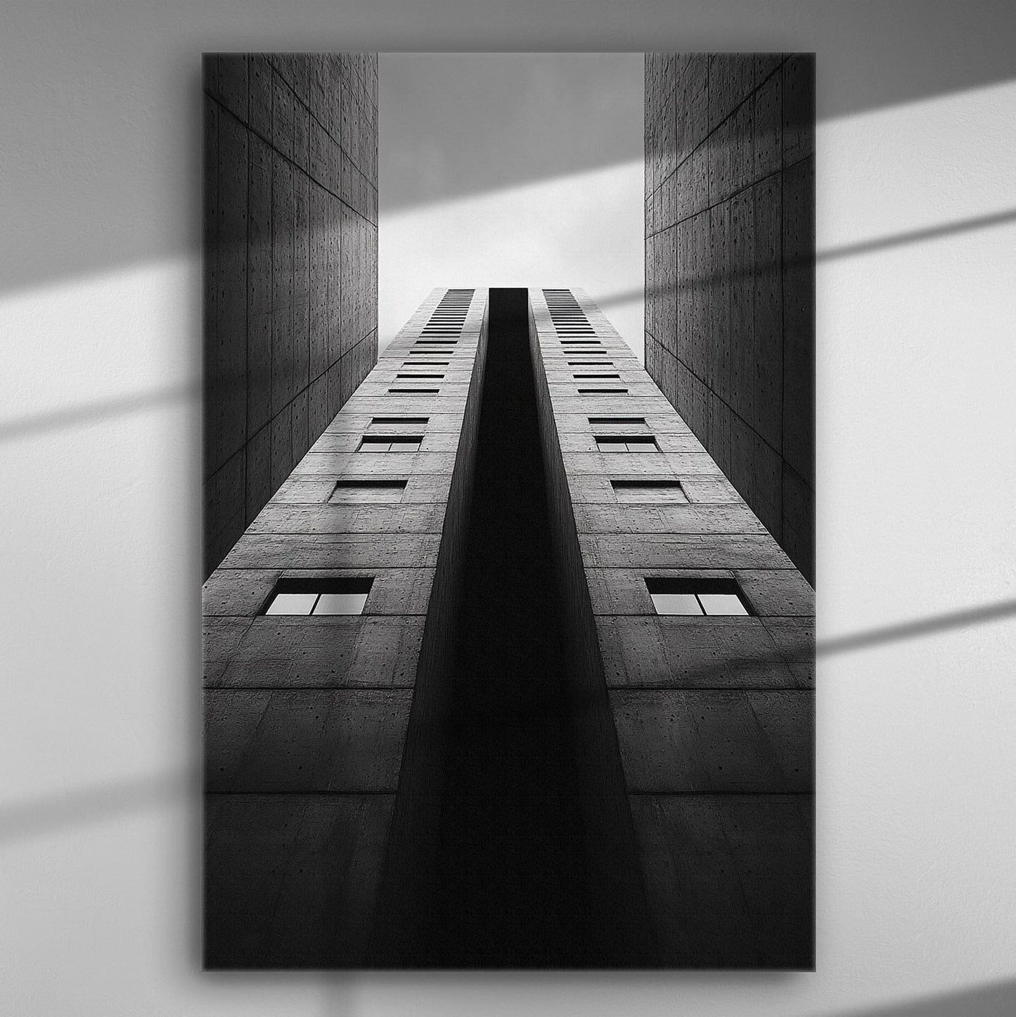 A high-contrast black and white photo of a tall building looking up into the sky, creating a sense of depth and height.