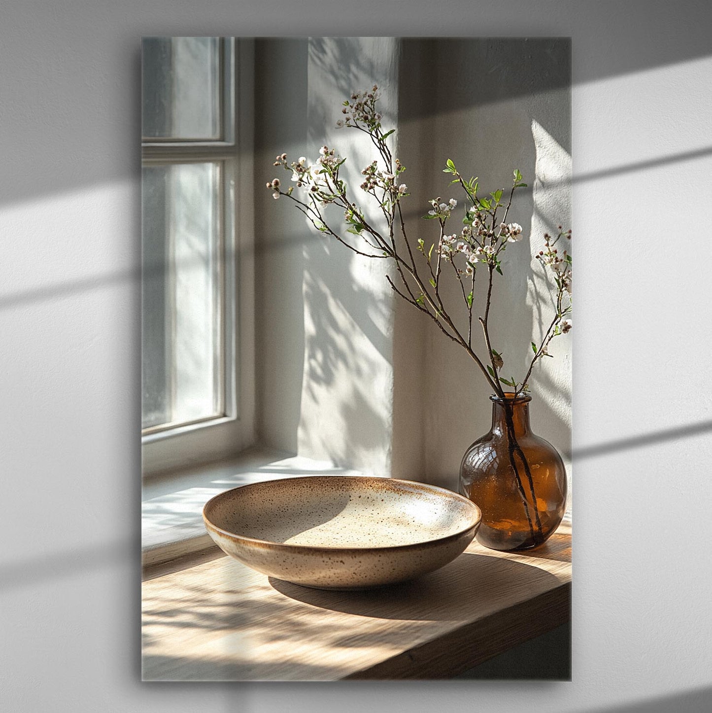 A serene setting with a window, natural light, and decorative branches in a vase on a wooden surface.