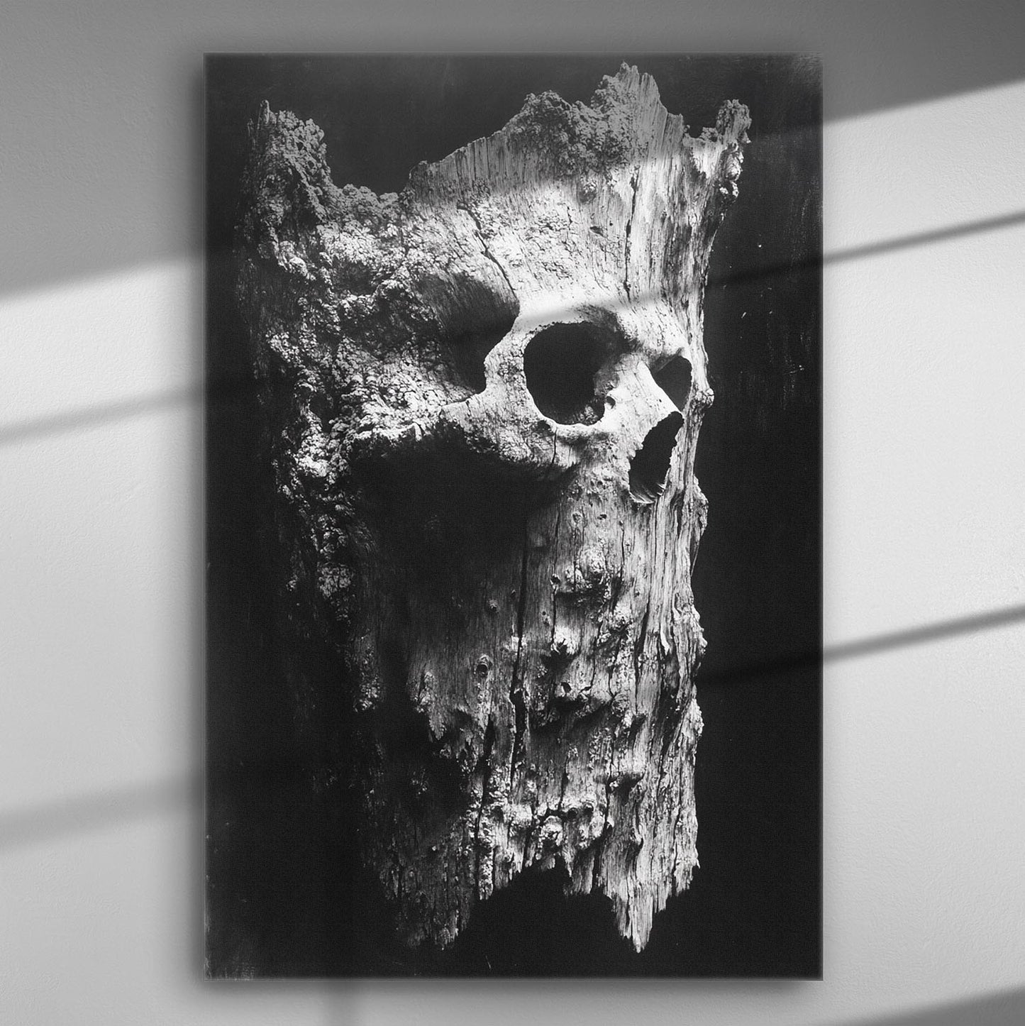 Black and white image of an aged tree resembling a skull structure in dramatic lighting.